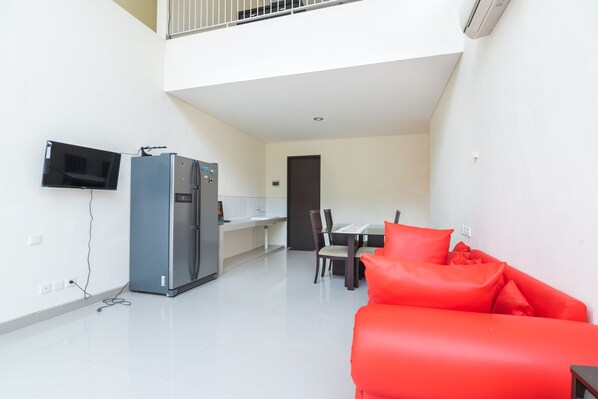 Un apartamento moderno con comedor, cocina y sala de estar con un sofá rojo.