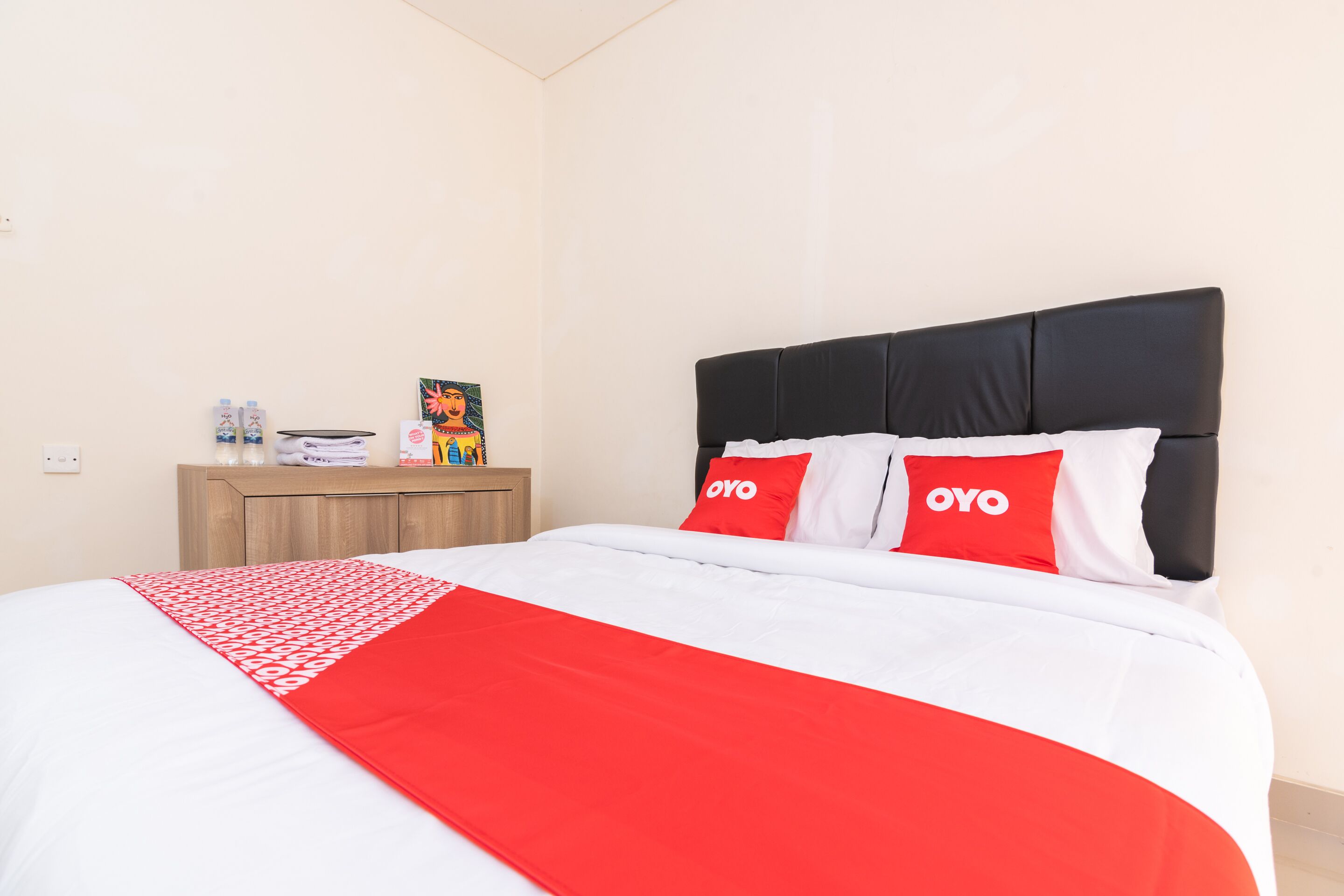 A hotel room with a bed, a nightstand, and a wall-mounted shelf.