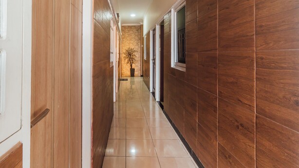 A hallway with wooden paneling, a tiled floor, and a potted plant. - OYO 2010 Satria Guest House (Ambon)
