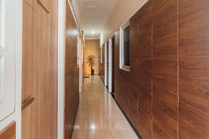 A hallway with wooden paneling, a tiled floor, and a potted plant. - OYO 2010 Satria Guest House (Ambon)
