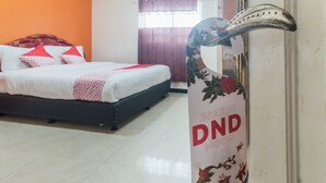 A hotel room with a bed, a sign with 'DND' written on it, and a window with curtains. - OYO 2010 Satria Guest House (Ambon)