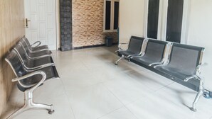 A waiting area with four black office chairs and a white tiled floor. - OYO 2010 Satria Guest House (Ambon)