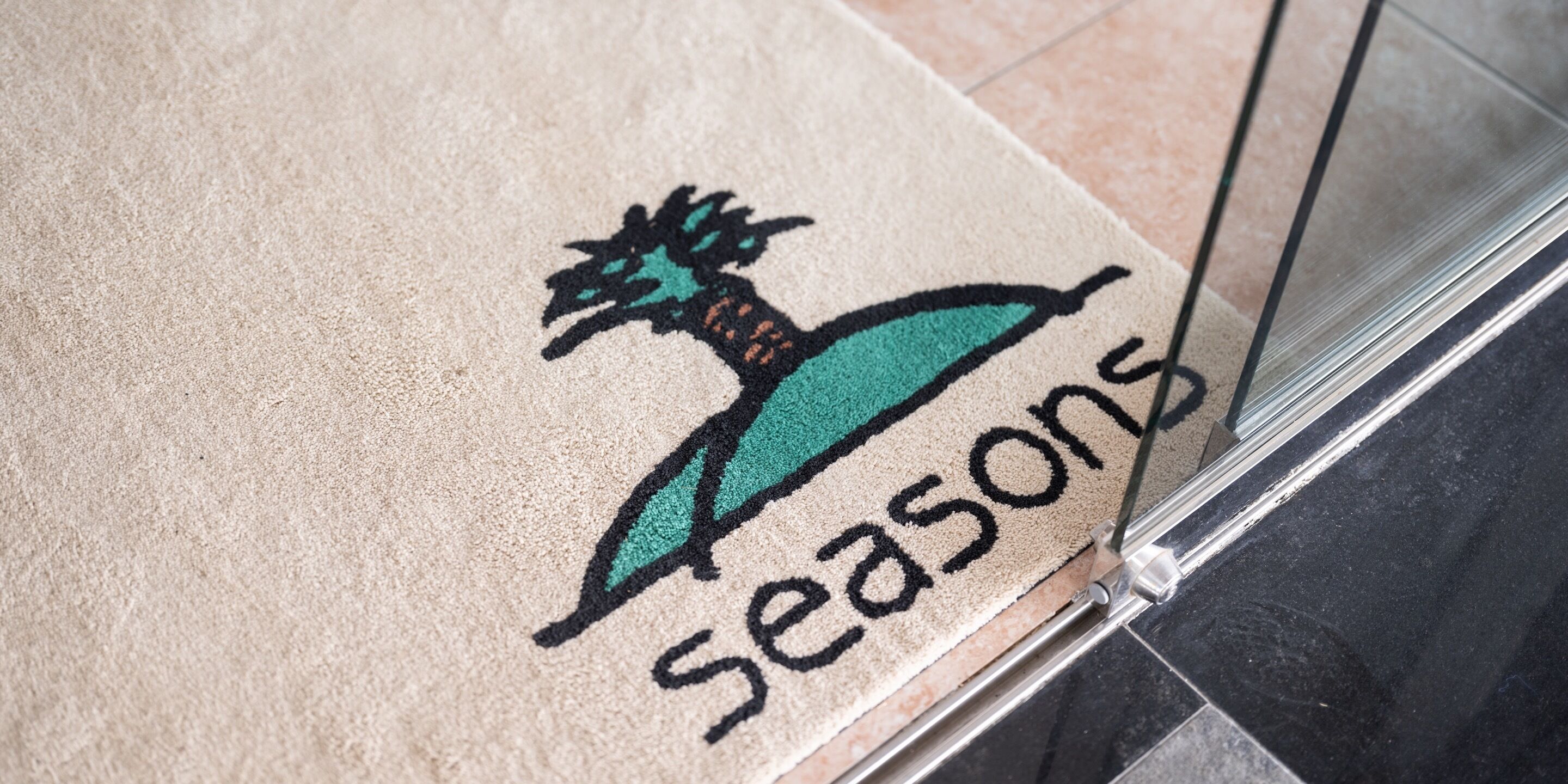 A doormat with a palm tree and the word "Seasons" on it.