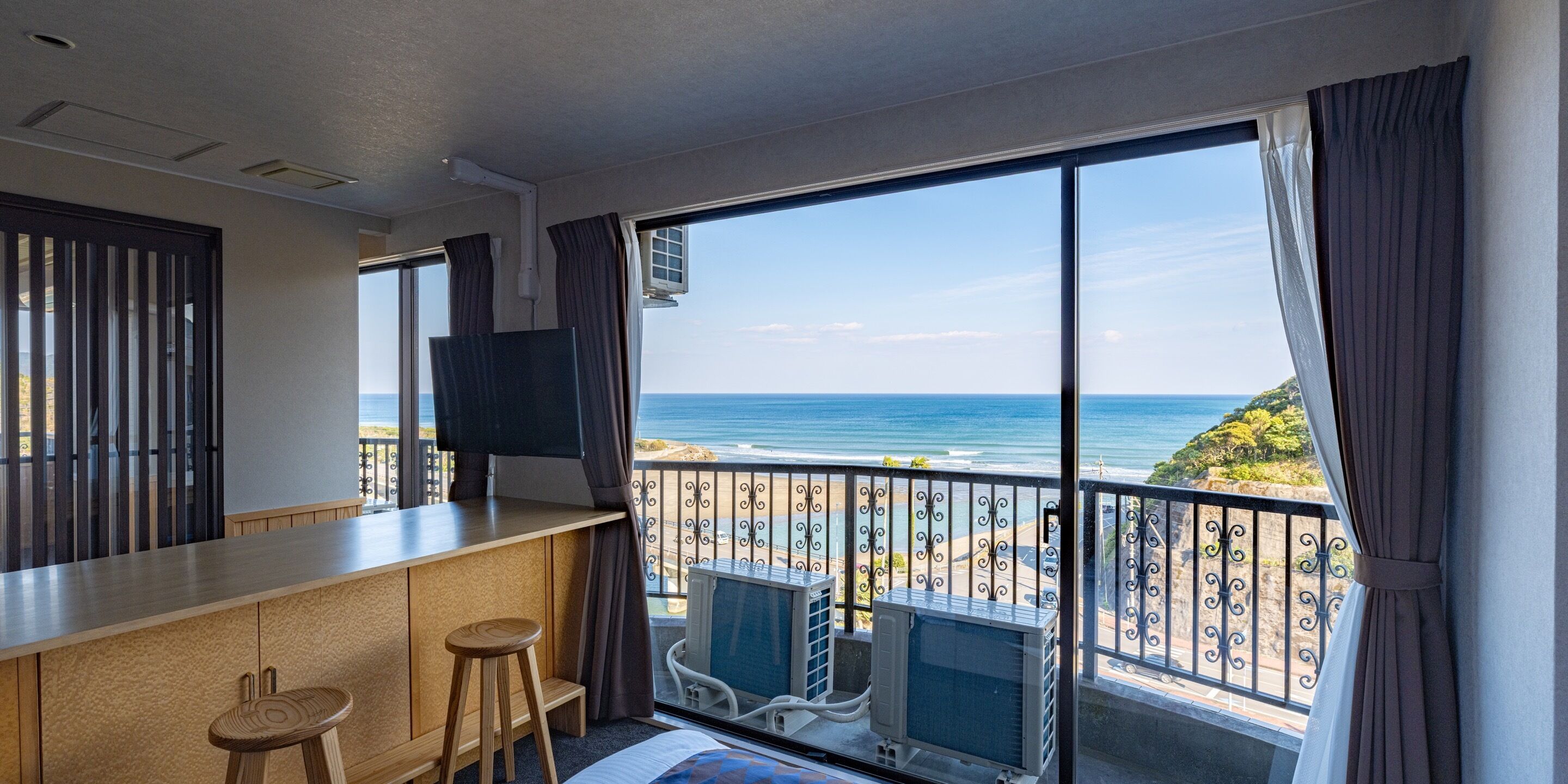 Habitación de hotel con balcón, televisión y minibar.