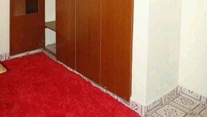 Une pièce avec une grande armoire en bois, une moquette rouge et des carreaux de sol à motifs.