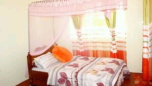 Un lit simple avec un baldaquin, une table de chevet et des rideaux.