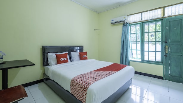 A hotel room with a bed, a desk, and a window with curtains.
