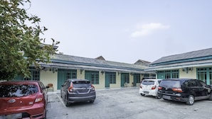 A parking lot with several cars parked in front of a building with green doors and a tiled roof.