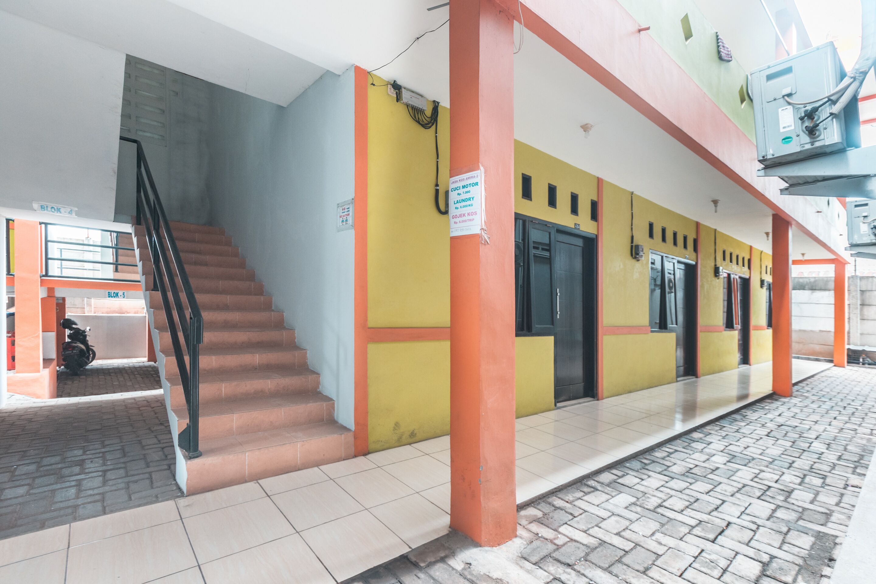 A building with a staircase leading to an entrance, a sign indicating a motor laundry service, and a tiled floor.