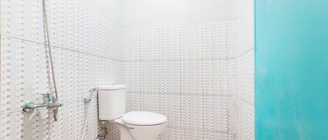 Un baño pequeño con inodoro, ducha y paredes de azulejos.
