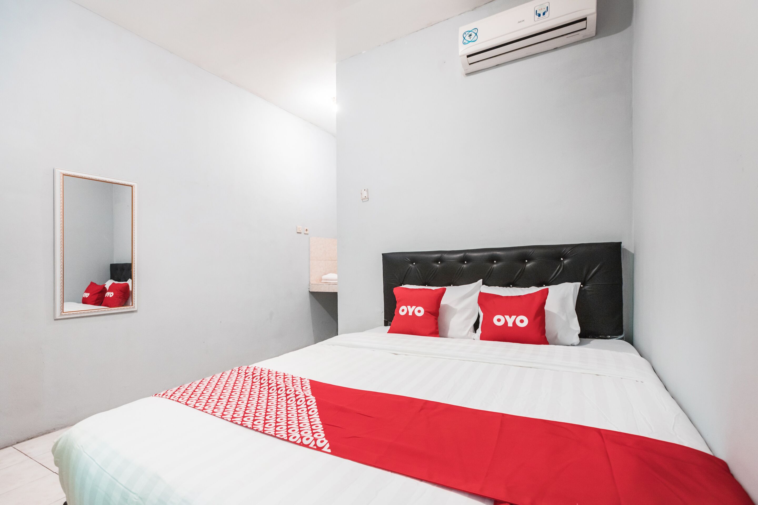 Een hotelkamer met een bed, een spiegel en een airconditioning.