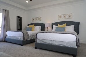 A hotel room with two beds, a large window with curtains, and a framed picture on the wall.