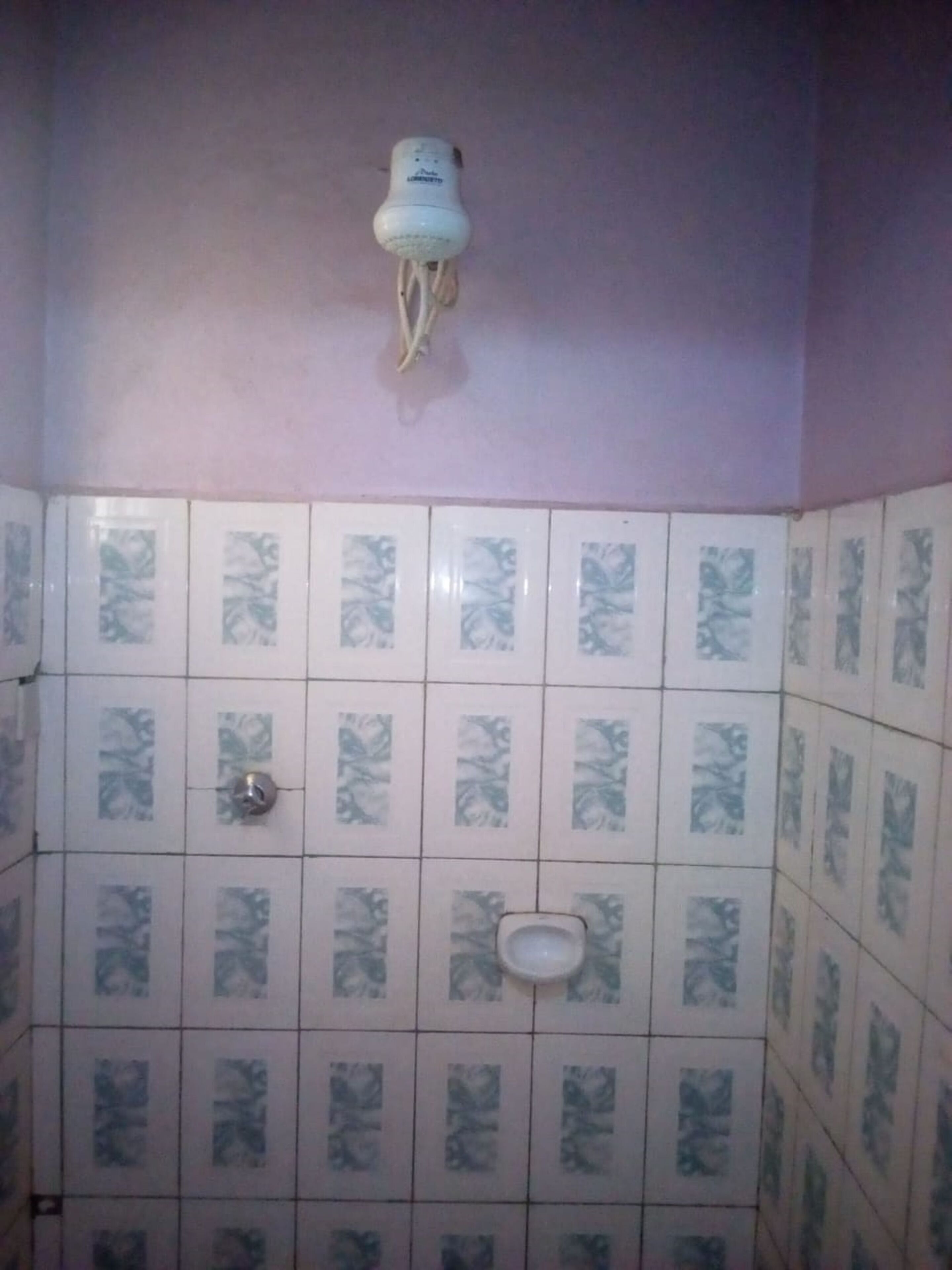 A bathroom with patterned tiles, a toilet, a sink, and a wall-mounted light fixture.