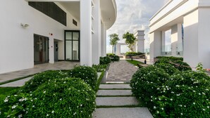 Een modern gebouw met een centrale pad, omlijst door strakke struiken en witte bloemen.