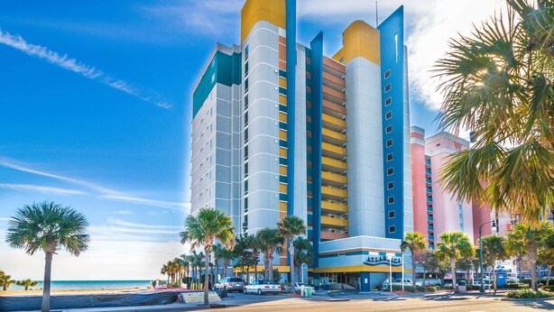 Un hôtel à plusieurs étages, doté d’un design moderne, de balcons et offrant une vue sur la plage.