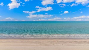 Une plage avec une eau d’un bleu limpide et un rivage sablonneux.