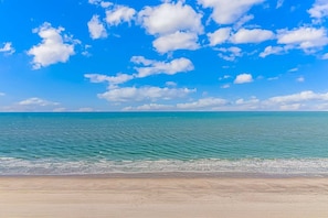 A beach with clear blue water and a sandy shore.