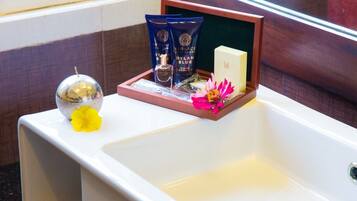 A bathroom with a white sink, a decorative mirror, and toiletries in a wooden tray.