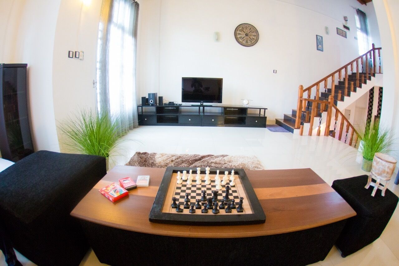 Un salon avec un jeu d’échecs, un téléviseur et un escalier.
