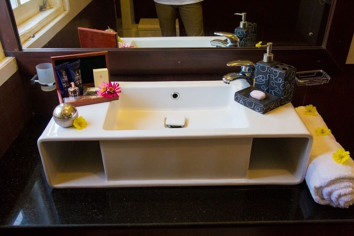 A bathroom sink with a mirror, toiletries, and a towel.