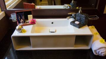 A bathroom sink with a mirror, toiletries, and a towel.