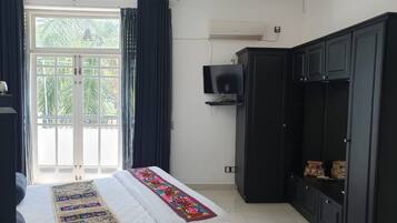 Un dormitorio con cama, televisión, armario y ventana con cortinas.