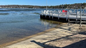 A sandy beach with a dock and a flag. - Weirs Beach - PRIME LOCATION!!!  (Weirs Beach)