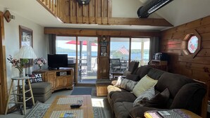 A spacious living room with a wooden staircase, a large window, a wooden ceiling, and a view of the outdoors. - Weirs Beach - PRIME LOCATION!!!  (Weirs Beach)