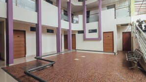 Un atrio de varios niveles con suelo de baldosas, pilares morados y una escalera.