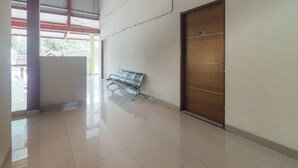 Un pasillo con un banco, una puerta de madera con placa de número y suelo de baldosas.