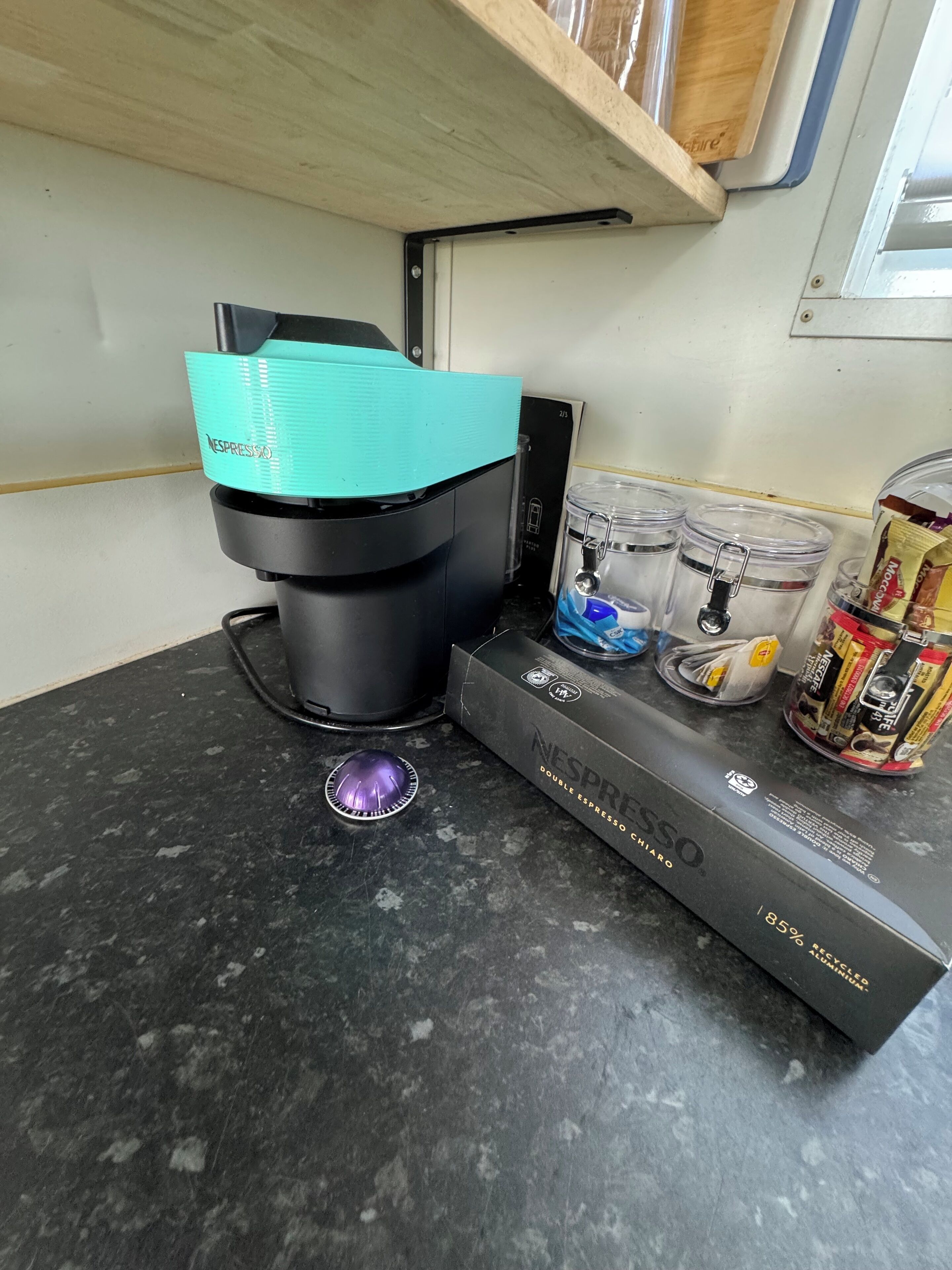 A coffee machine, a water dispenser, and a box of Nespresso capsules on a countertop.