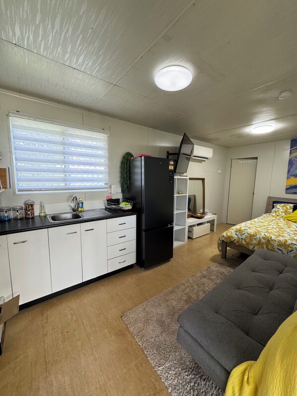 A compact living space with a kitchenette, a bed, and a small seating area. - Red Dog's Retreat and Pup with a pool & ocean views. WiFi & Linen included (Dundee Beach)