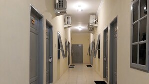 Een hal met deuren aan beide kanten, airconditioningunits aan de wanden en zwarte matten op de vloer.