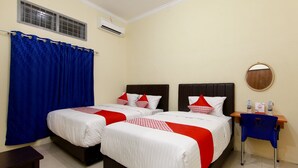 Een hotelkamer met twee bedden, een klein bureau, een stoel en een spiegel aan de muur.