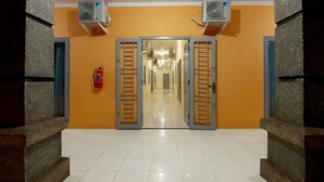 Een gang met een spiegelwand, twee airconditioners en een brandblusser.