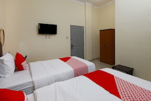 Habitación de hotel con dos camas, televisión, armario y una mesita.