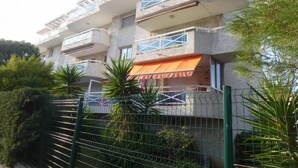 A multi-story building with balconies, a fenced area, and some greenery. - APARTMENT T3 - Private parking - 300 m SEA & BEACH (Fréjus)