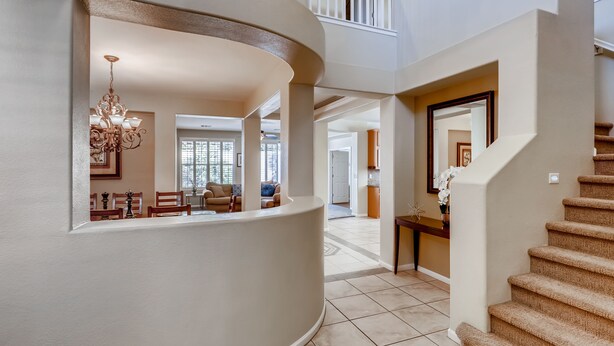 A spacious, curved hallway with a staircase leading to a second floor. - Vegas Themed 6BR · Game Room · 2 Suites · EV  · Spacious Retreat For 14 Guest (North Las Vegas)