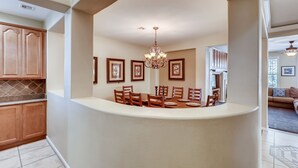 A dining area with a chandelier, framed pictures on the wall, and wooden chairs and table. - Vegas Themed 6BR · Game Room · 2 Suites · EV  · Spacious Retreat For 14 Guest (North Las Vegas)