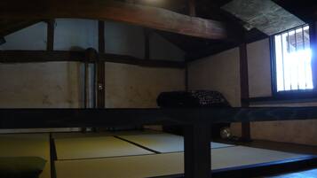 A traditional tatami mat room with a low ceiling and wooden beams.