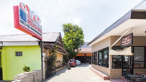 Une vue de rue avec un café appelé « Caffe Pelita Mas » et une enseigne indiquant « Wisma Pelita Mas », avec le numéro de l’immeuble.