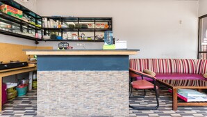 Une cuisine avec un mur recouvert de pierres, un comptoir sur lequel sont disposés divers ustensiles et accessoires, et un canapé à rayures dans l’espace salon.