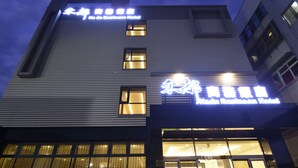 Un hotel moderno con letreros iluminados en un idioma extranjero, ventanas amplias y un diseño arquitectónico depurado.