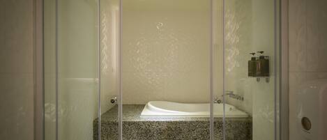 Une salle de bain moderne dotée d’une douche à parois de verre, d’une baignoire intégrée et d’un comptoir en granit.