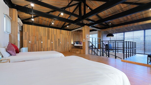 A modern hotel room with two beds, wooden walls, a balcony with a view, and a staircase. - HOTALU Universal Vacation Kan (Osaka)