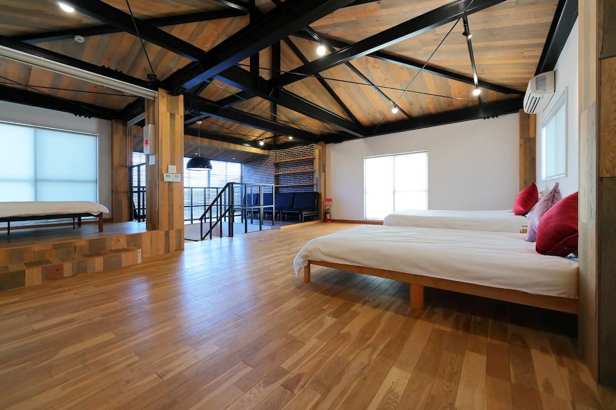 Une pièce spacieuse dotée d’un grand lit, d’un parquet et d’un plafond haut avec des poutres apparentes.