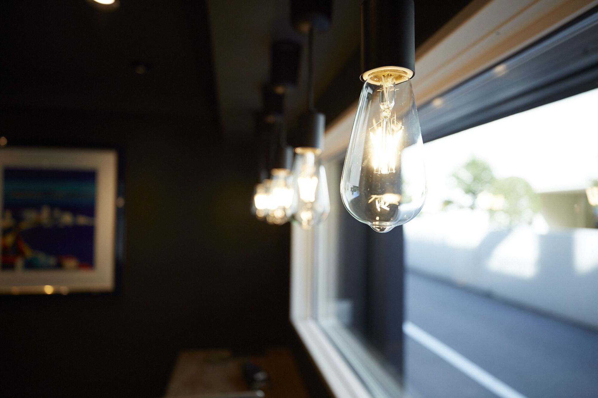 A row of hanging pendant lights with exposed bulbs in a dimly lit room.