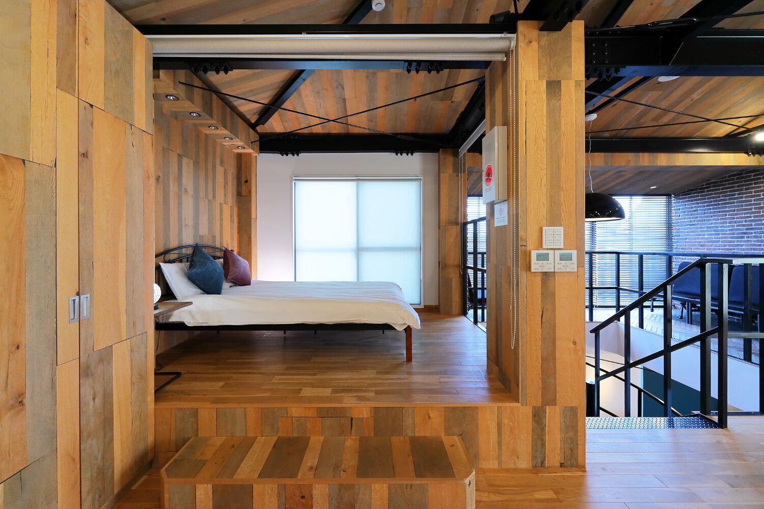 Ein Schlafzimmer mit einem Bett, Holzwänden, einem Fenster und einer Treppe, die zu einem Balkon führt.