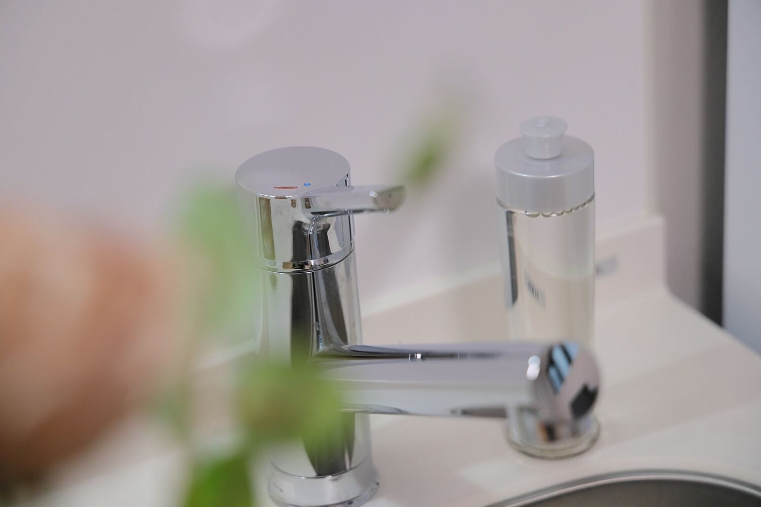 A modern bathroom with a chrome faucet and a soap dispenser.