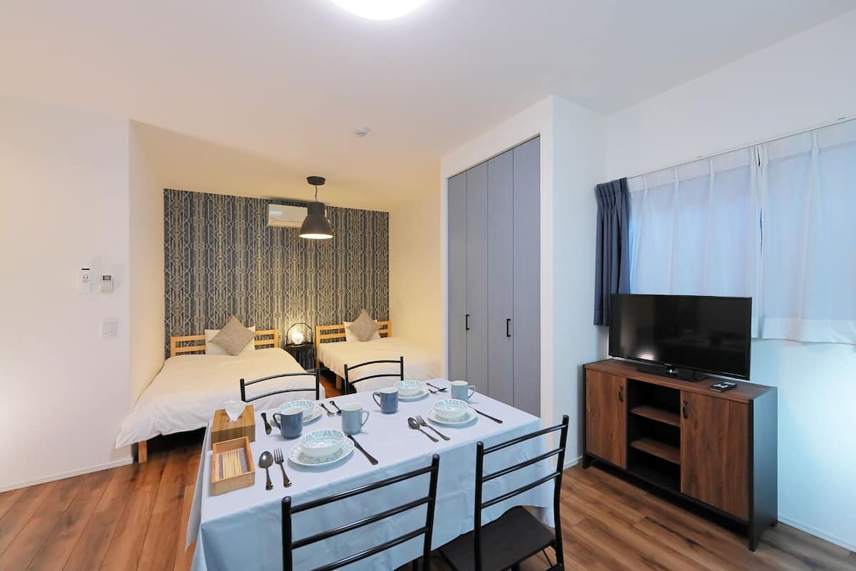 Une chambre d’hôtel de taille modeste, comprenant un lit simple, une table à manger pour deux personnes, un téléviseur et une armoire.